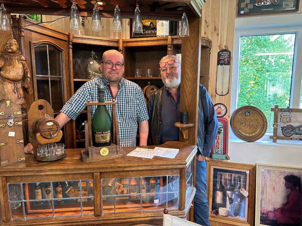Frank Landholt (f.v.) og Svein Eriksen bak bardisken i bruktbutikken sin..