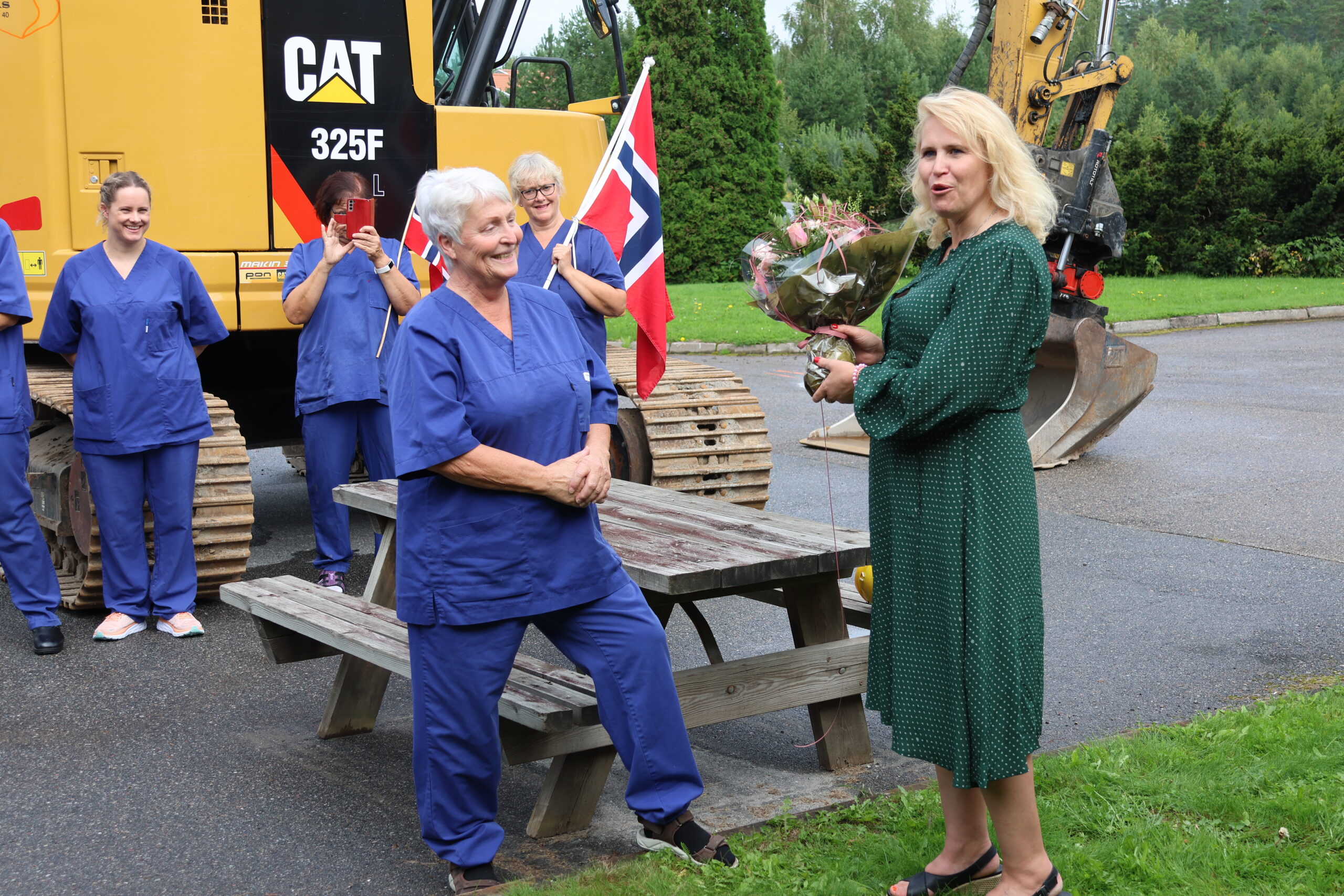 Eline Trandem Dahl (t.v) fikk ta i mot blomster av ordfører Kamiila Thue. Trandem Dahl kunne fortelle at hun hadde vært i jobb på kjøkkenet siden 1980.