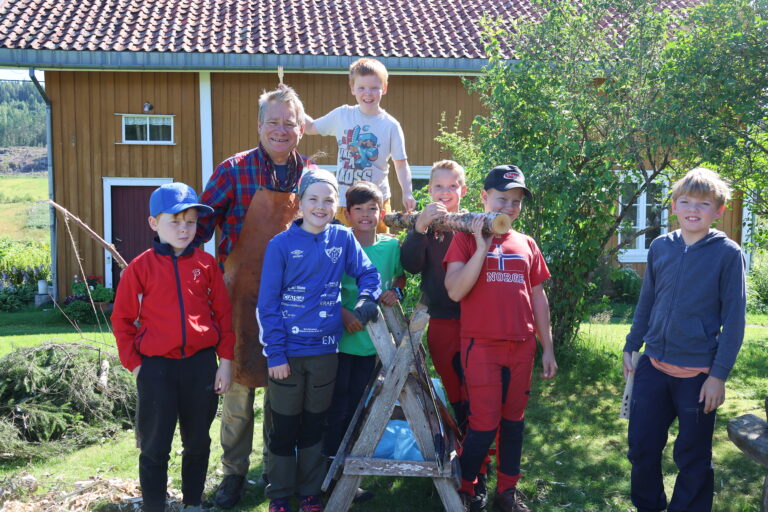 Hroar Gomsrud (t.v.) lærer Eivind Falk, Eira Nordal, Christoffer Utgården, Thor Kristian Gomsrud (bakerst) Martin Brøderud, Thomas Brøderud og Øivind Sørli har vært på spikkekurs på Almenninga i sommerferien.