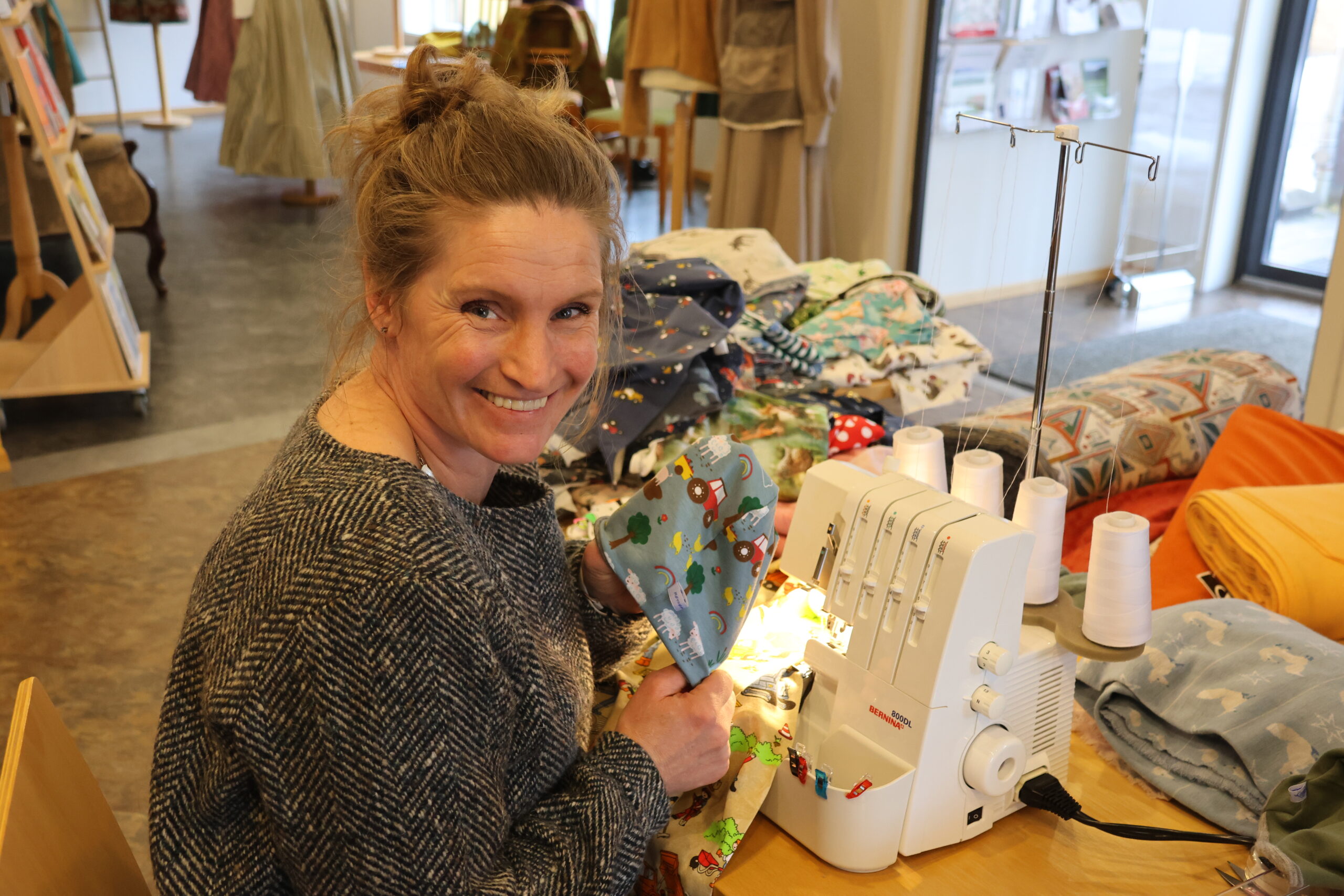 Veslemøy har tatt med seg sine symaskiner til Tyrielden. Her viser hun frem hvordan hun kan bruke stoffet fra en slitt ullundertrøye som for i en lue til en baby.