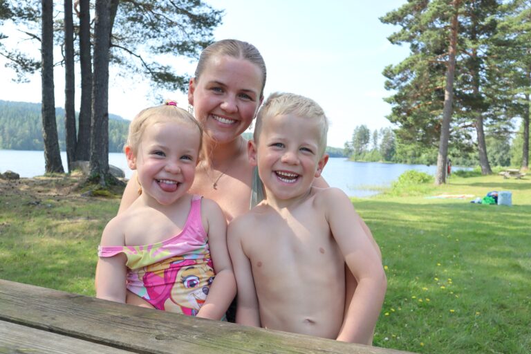 Caroline Dahl, Erle Dahl Stevik (3) og Emil Dahl Stevik (5) trives godt på badeplassen ved Søndre Øyungen. Gulrota er den åpne sommerkiosken.