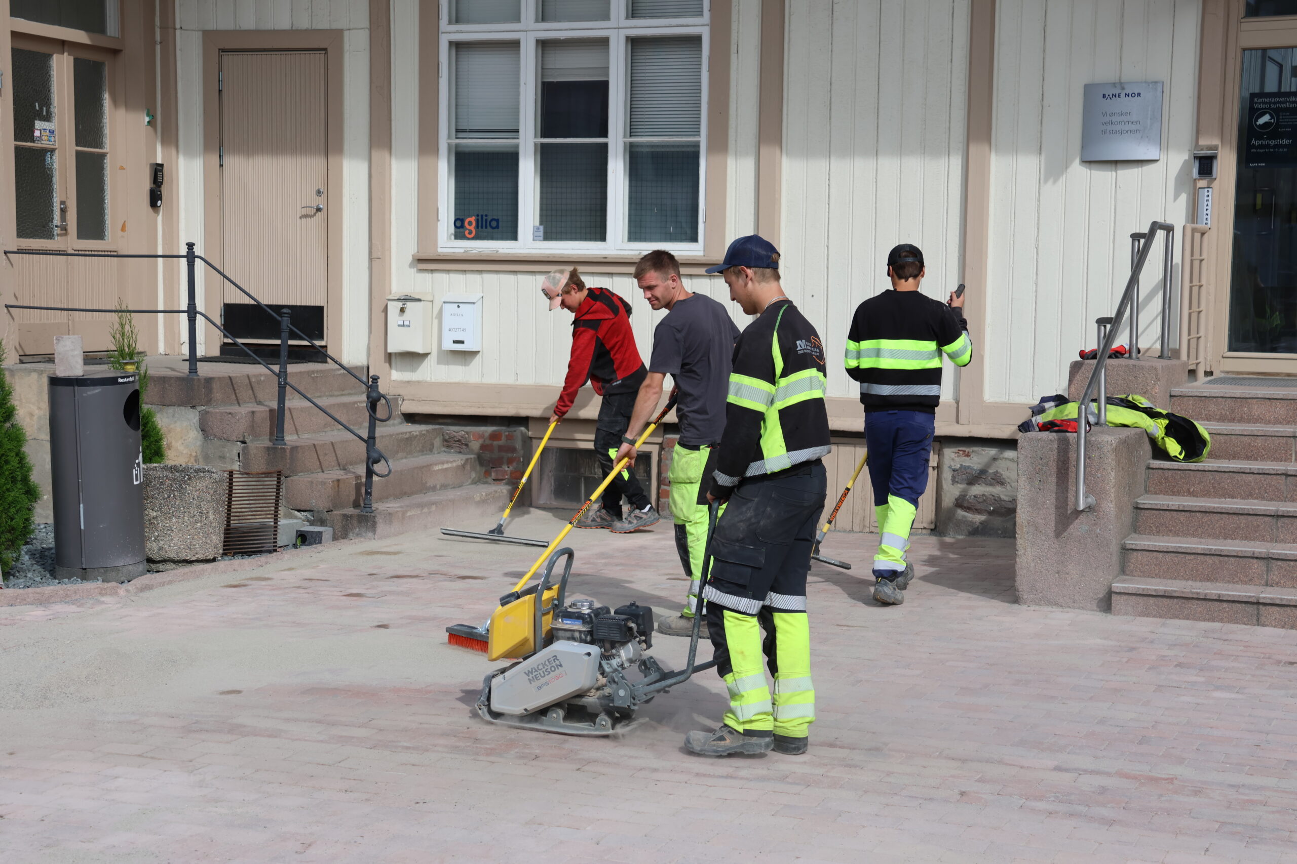 Det er utført mye arbeid på stasjonstomta. Blant annet er 600 kvadratmeter med beleggningstein plukket opp, renset og lagt igjen. Her har Simen Tuhus styr på hoppetussa, mens Simon Melby, Alexander Smedtorp og Anton Aurbakken hiver på fugesand mellom steinen.