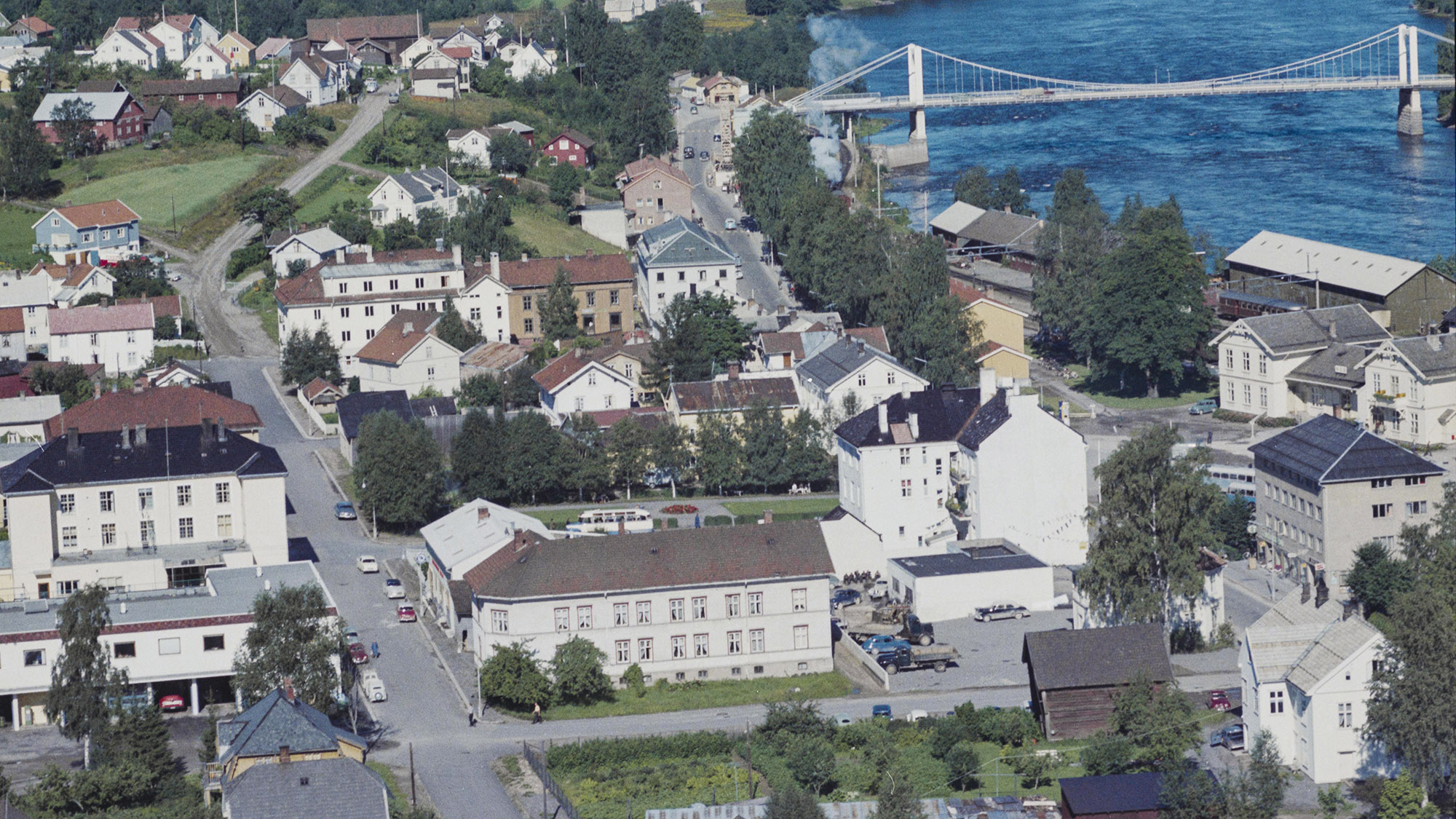 Jernbanegata og Glommengata i 1961. Nede til venstre ligger lagerbygget til Gustav Solvang og Østbanernes Forbruksforening. I Glommengata synes byggekranene som reiser det nye Nylænder-bygget i mur. Til høyre mot jernbaneplassen ligger Tømmerås-gården. Nede foran ligger Lomsnæsgården, Bilco og Kapteinsgården, som alle ble revet på 70-tallet.