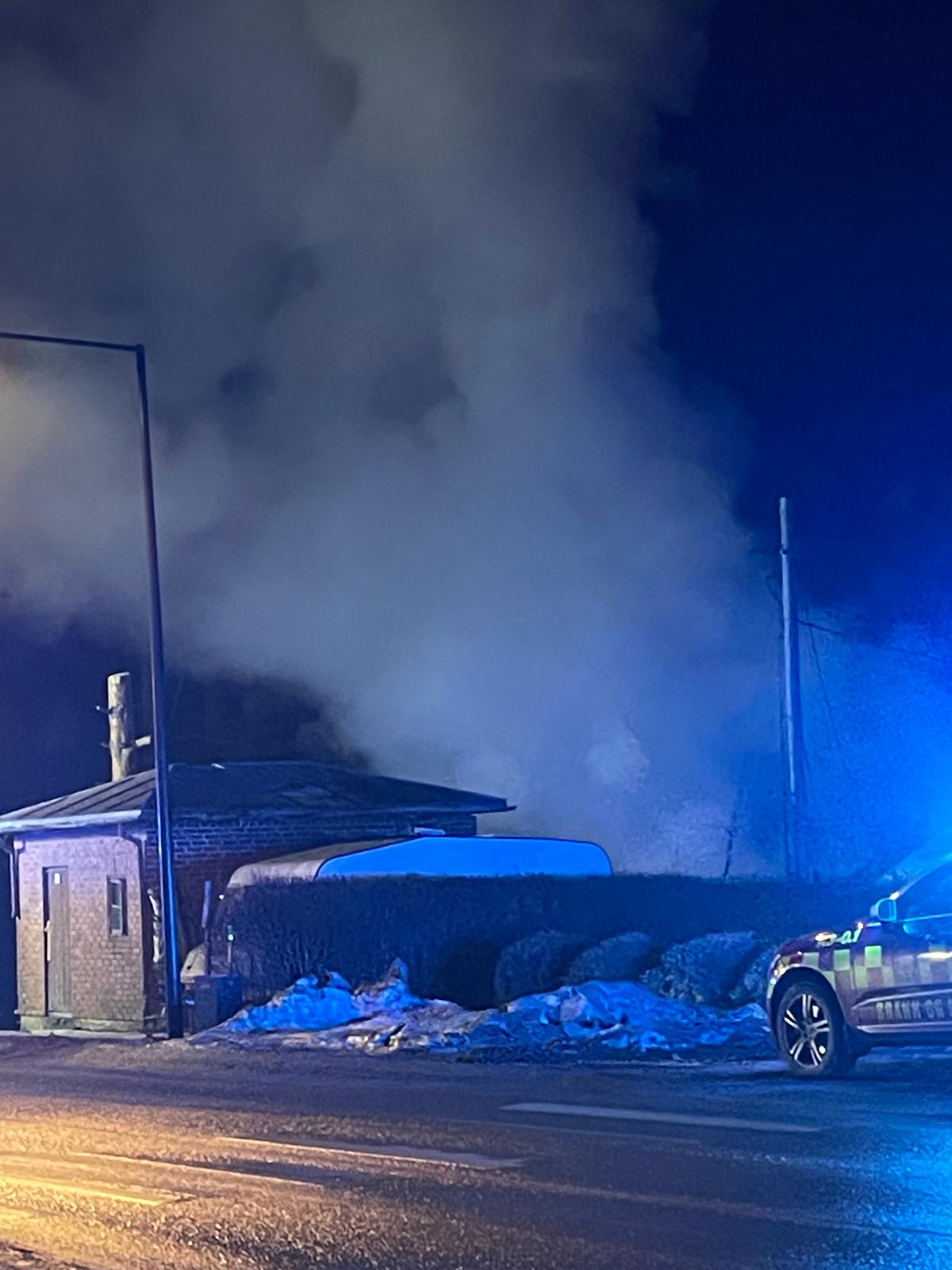Røyken stiger til himmels fra bygningen som står i brann. Bygningen er skjult bak huset foran på bildet.
