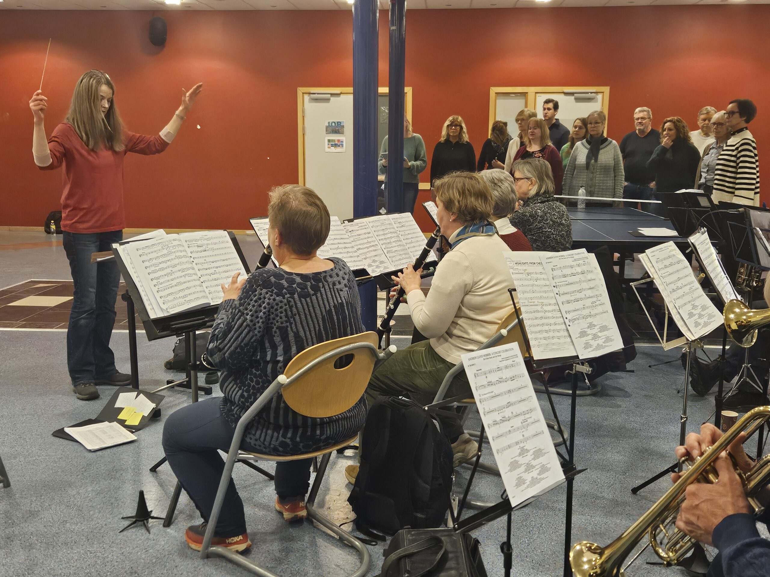 Koret og korpset er samlet for fellesøving en drøy uke før konserten, her med dirigent Hilde Finsrud som har full kontroll på både kor og korps.